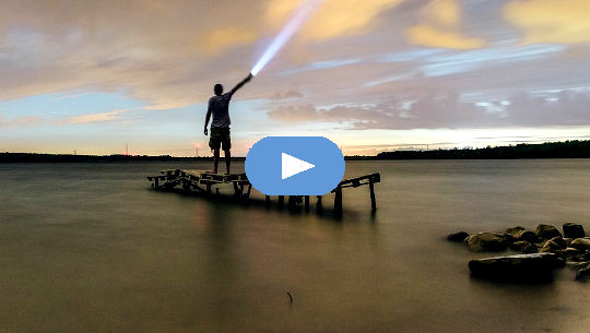 Blessing for Spiritual Seekers and for People Suffering from Depression man standing on a dock shining a flashlight into the sky
