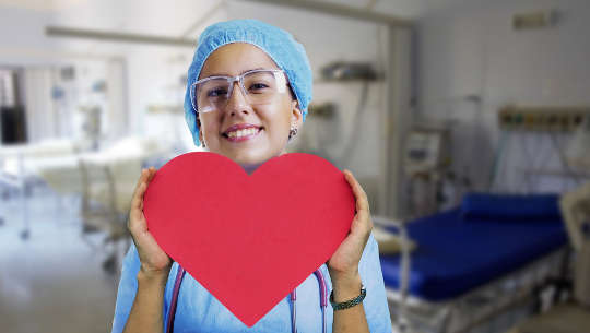 Communicating with ICU Staff When Your Loved One Is a Patient smiling nurse holding up a paper cut out in a heart shape