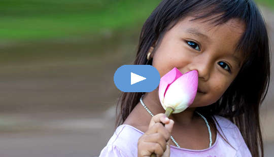 The Lotus Within You Awakes smiling young girl holding an unopened lotus flower