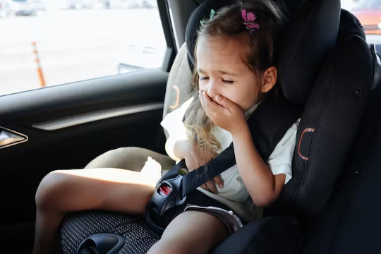 child experiencing motion sickness in a car seat