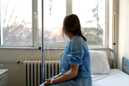 woman sitting on the side of a hospital bed