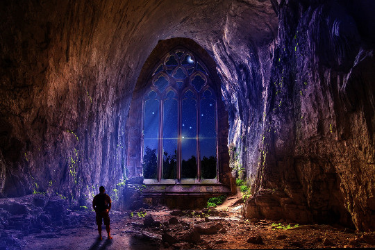 How the Divine Speaks: Coincidence, Synchronicity, Disease a man in a cave with a huge arch opening to the night and sky