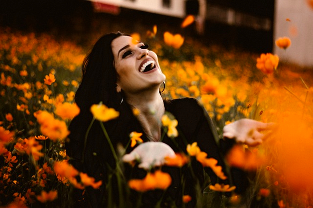 How To Grow Your Own Happiness: You Are A Garden and a Gardener a woman laughing in a field of bright orange flowers