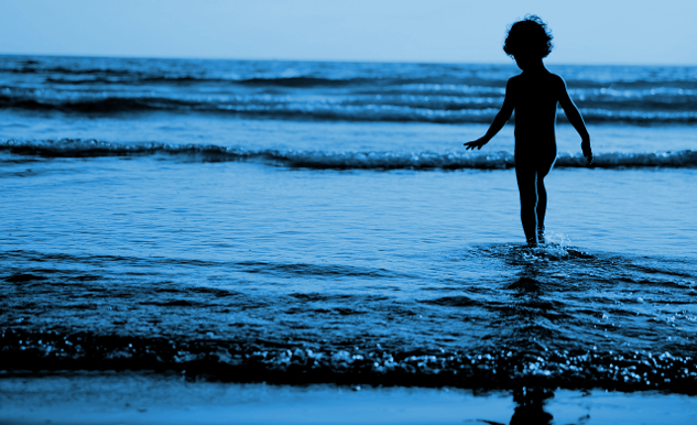 We’re at the Tip of the Subtle Energy Iceberg young boy standing in the water at the edge of the waves rippling in