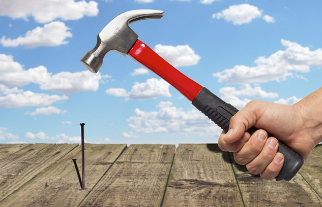 Can I Do This? Understanding The Fear of Failure and The Power of Intention a hand holding a hammer and getting ready to strike a nail