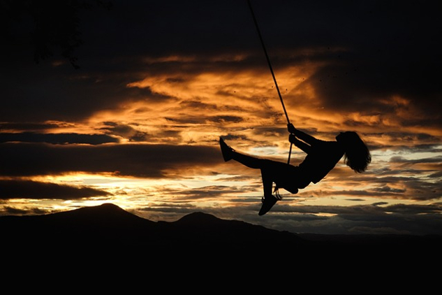Five Easy Ways to Increase the Joy in Your Life woman on a swing, happily swinging through the air. at sunset