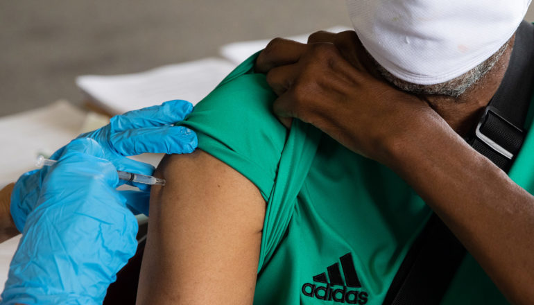 person holds up t-shirt sleeve for injection